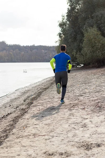 Man jogging by the lake with smart phone armband. — Stock Photo, Image