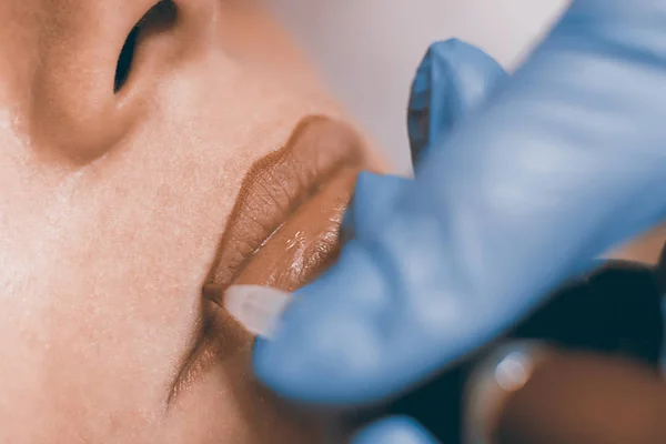 Maquillaje permanente. Cosmetólogo aplicando maquillaje permanente en los labios . — Foto de Stock