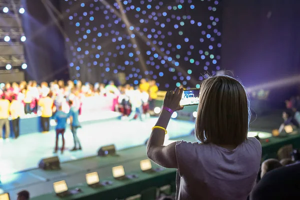 Girl with a smartphone taking photo of concert stage — Stock Photo, Image