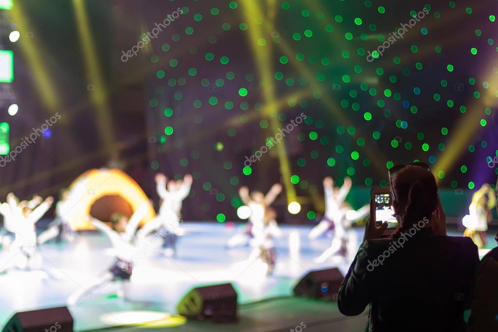 Girl with a smartphone taking photo of concert stage 