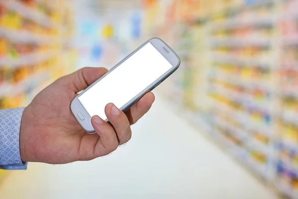 Hombre revisando la lista de compras en su teléfono inteligente en el supermercado . —  Fotos de Stock
