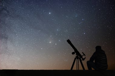 Astronomi teleskopuyla yıldızlara bakarak adam. 