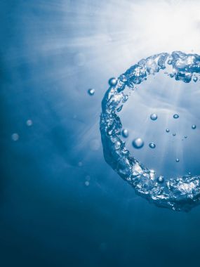 Bubble ring underwater ascends towards the sun. clipart