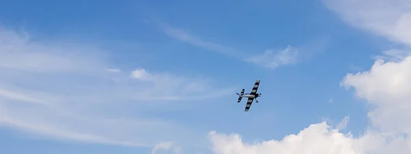 Avión de juguete controlado por radio contra el cielo azul con nubes blancas — Foto de Stock