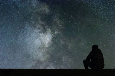 Samanyolu. Gece gökyüzünde yıldızlar ve siluet yalnız adam arıyorum
