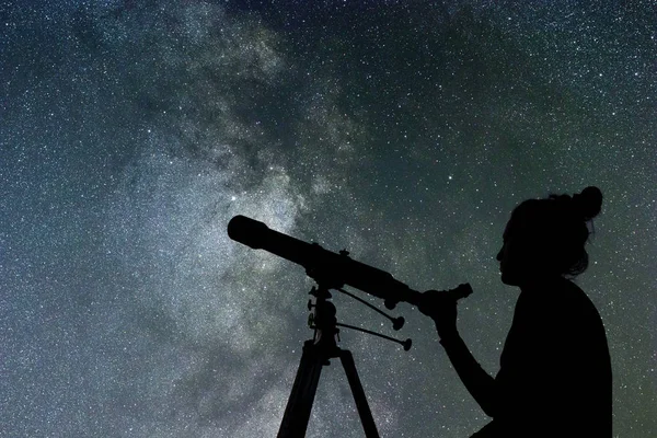 女人用望远镜在她旁边看着的星星 — 图库照片