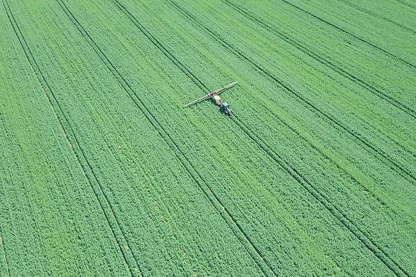 鸟瞰农业机械在大绿色上喷洒化学品 — 图库照片