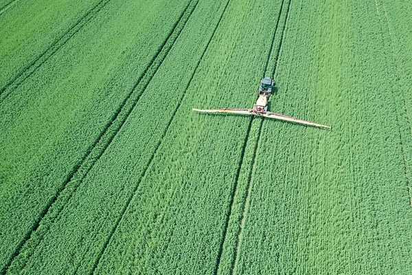 Aerial view Farm machinery spraying chemicals on the large green