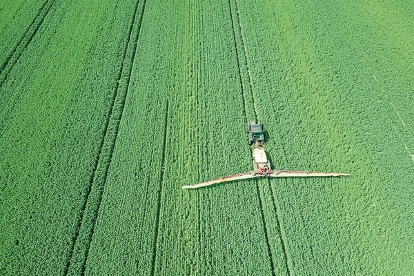 Aerial view Farm machinery spraying chemicals on the large green