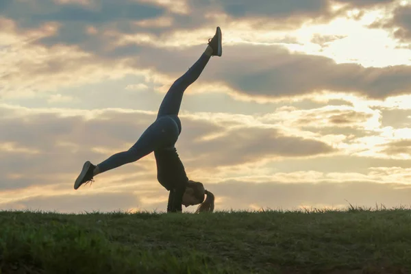 Mladá žena, která dělá přemet stranou na trávě ranní cvičení krásná — Stock fotografie