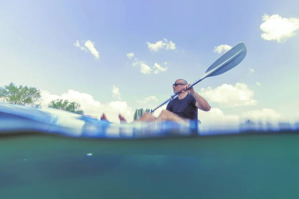 Młody człowiek kajakarstwo na jeziorze, kajakarstwo pod wodą, Split Shot — Zdjęcie stockowe