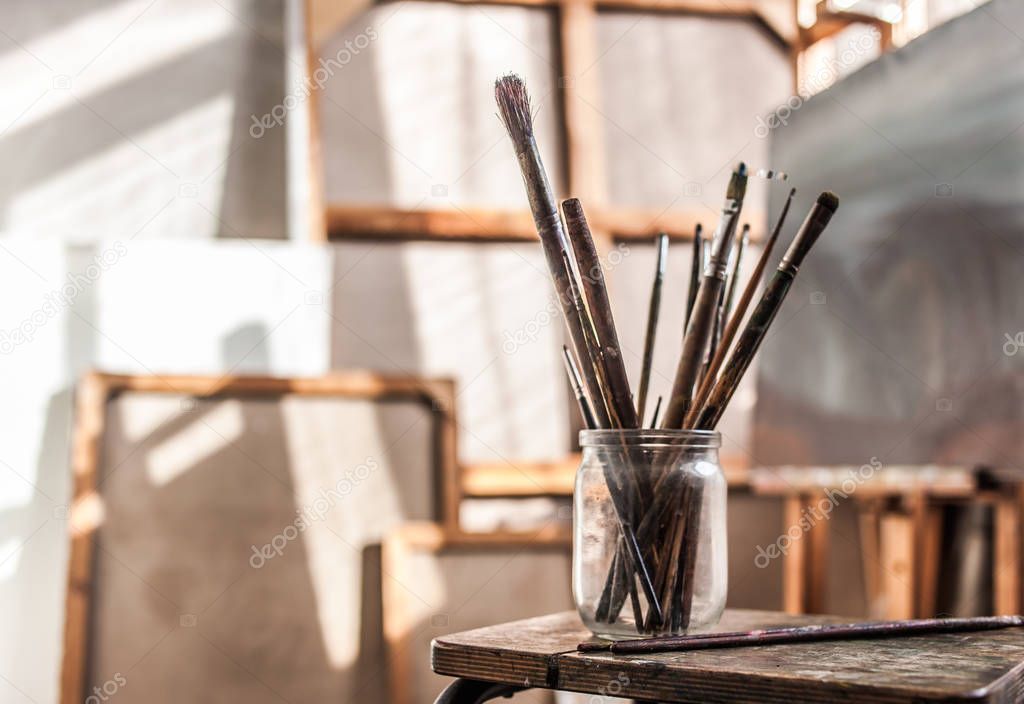 paintbrushes in glass on stool
