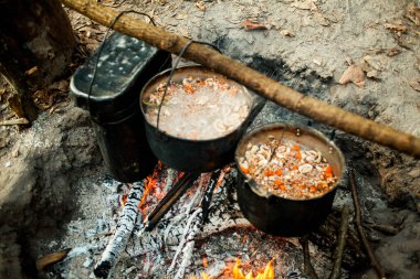 Ormanda kamp ateşinde lezzetli yemekler pişirmek. 