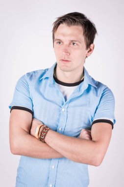 Yakışıklı çekici. resmi kıyafeti katlanmış silah ile genç adam ayakta, beyaz arka planı süre kamera bakıyor