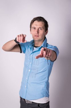 Resmi kıyafeti sevimli yakışıklı genç adam onun ellerini, ince ve sert parmaklar ayakta beyaz arka planı süre kamera ile puan tutar