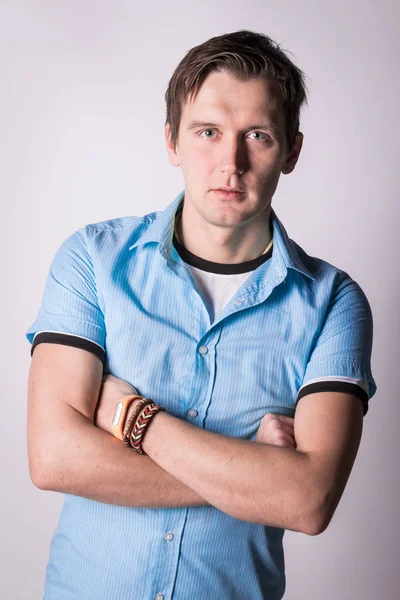 Yakışıklı çekici. resmi kıyafeti katlanmış silah ile genç adam ayakta, beyaz arka planı süre kamera bakıyor