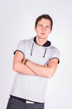 Yakışıklı çekici. resmi kıyafeti katlanmış silah ile genç adam ayakta, beyaz arka planı süre kamera bakıyor