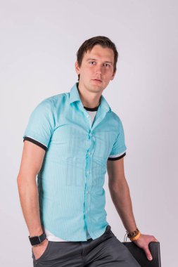 Yakışıklı çekici. genç adam resmi kıyafeti ceplerinde, el ele tutuşarak ayakta, gri arka planı süre kamera bakıyor