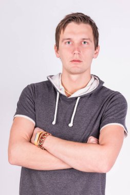 Yakışıklı çekici. resmi kıyafeti katlanmış silah ile genç adam ayakta, beyaz arka planı süre kamera bakıyor