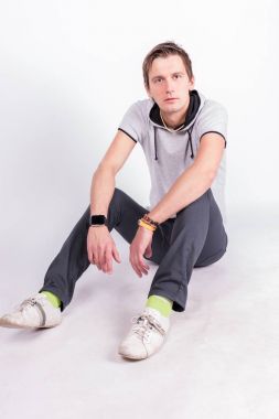 Yakışıklı çekici. ceplerinde elele resmi kıyafeti genç adam, kameraya bakarak oturur, beyaz arka plan