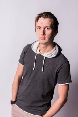 Yakışıklı çekici. genç adam resmi kıyafeti ceplerinde, el ele tutuşarak ayakta, beyaz arka planı süre kamera bakıyor