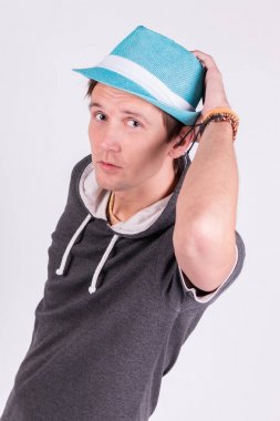 Yakışıklı genç adam resmi kıyafeti içinde büyüleyici mavi şapka beyaz arka plan tutar