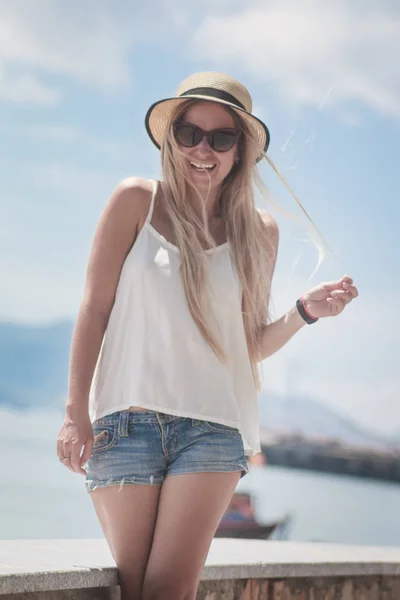 Belle femme debout sur le remblai de la ville et profitant de la vue, dans un chapeau de paille, le dos à la caméra — Photo