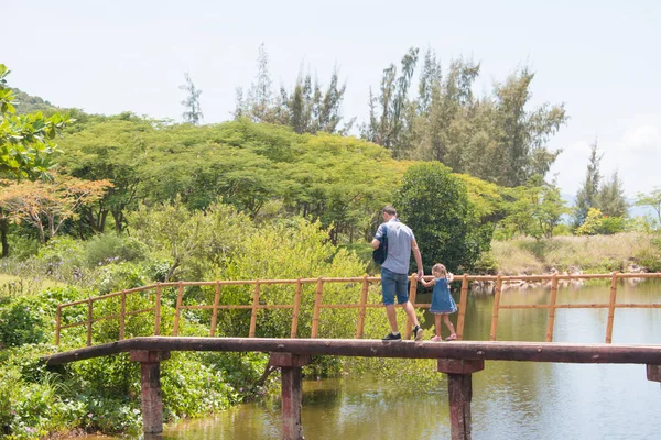 Feliz padre hombre con su pequeña hija caminando a través del puente marino de madera — Foto de Stock