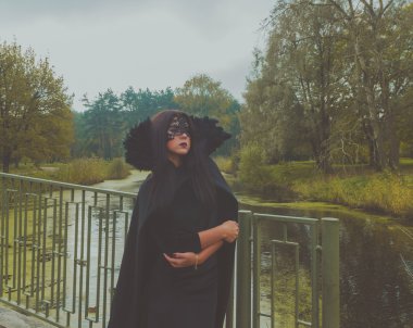 Köprünün kendisi kız siyah elbise ve maske kucaklayan