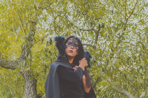 葉の間で黒マスクやドレスの女の子 — ストック写真