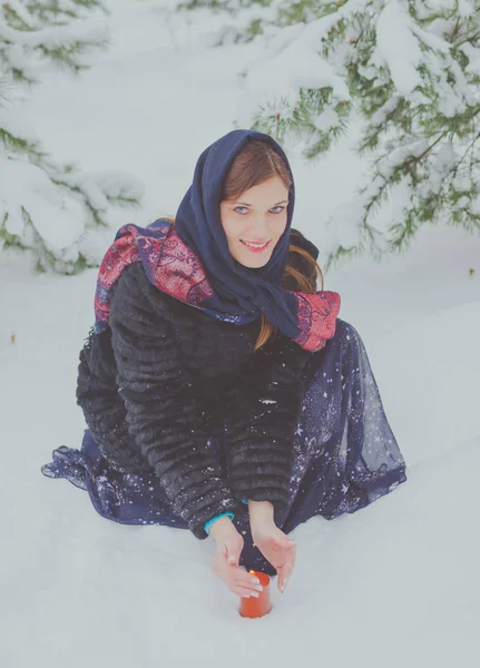 Beautiful girl with blue eyes in winter near Christmas trees with a candle. — Stock Photo, Image