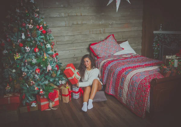 白いセーターでセクシーな女の子がクリスマス プレゼントを解体します。. — ストック写真
