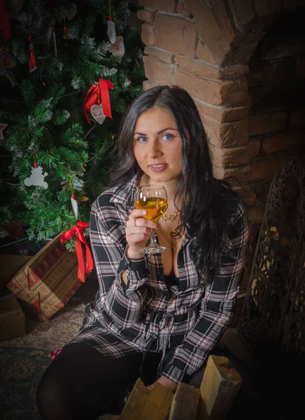 Ein Mädchen mit blauem am Baum mit einem Glas Wein zu Weihnachten. — Stockfoto