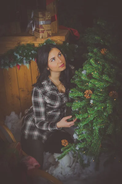 En el árbol de Navidad se sienta una chica con los ojos azules — Foto de Stock