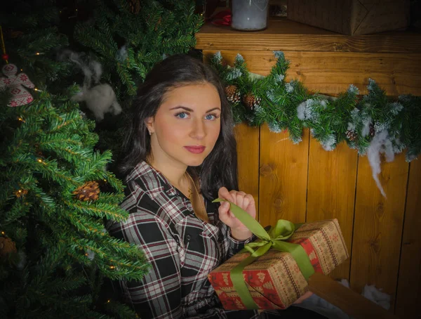 Cerca del árbol de Navidad con un regalo en las manos de una hermosa niña . — Foto de Stock