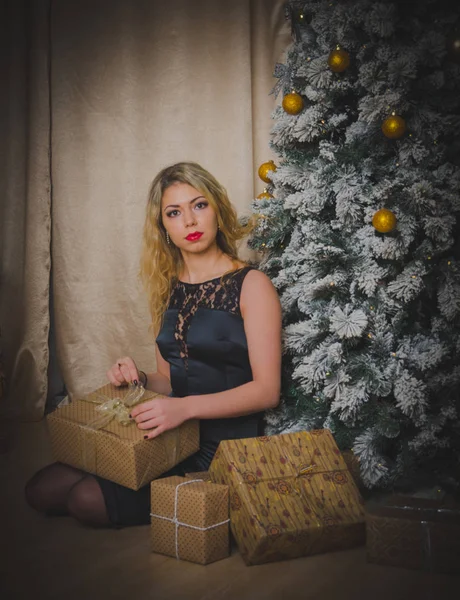 クリスマス ツリーの近く黒で一晩スパイシーな女の子をドレスします。 — ストック写真