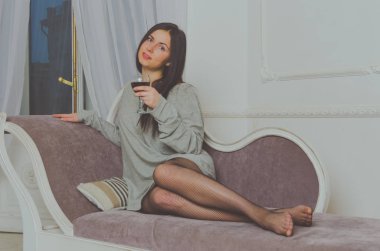 bir bardak şarap ile kanepede bir t-shirt çekici bir kız.