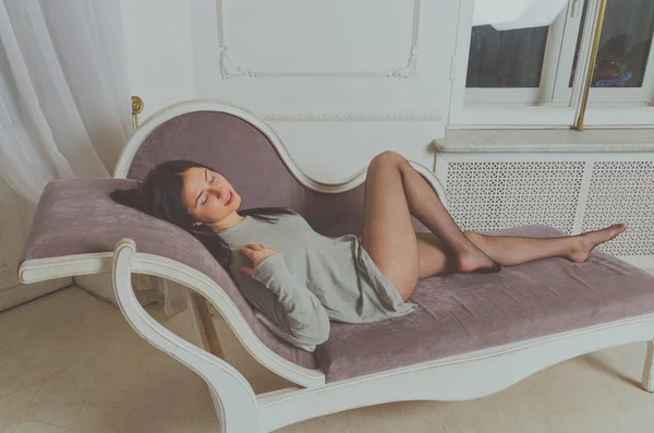 Attractive girl in t-shirt posing on a couch — Stock Photo, Image