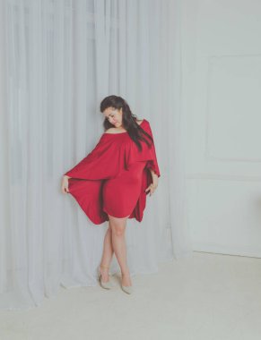 Bordo elbise giymiş güzel kız ayakta poz pencere