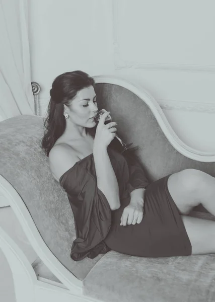 Czarny i biały, z winem na kanapie piękna dziewczyna w sukience — Zdjęcie stockowe