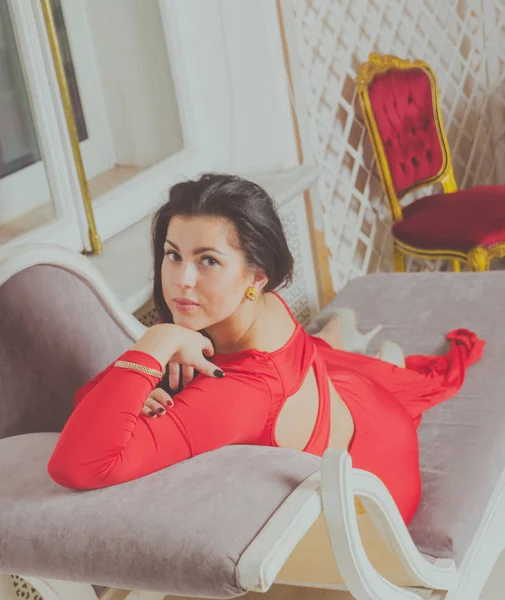 On the couch sexy girl in a red dress — Stock Photo, Image