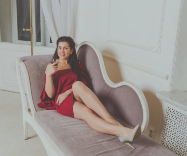 kanepede kadeh şarap ile Kırmızı elbiseli güzel kız