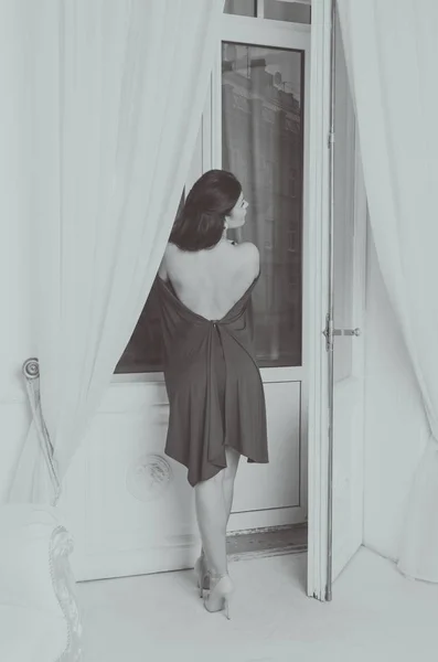 Μαύρο και άσπρο, κοντά στο παράθυρο για μια όμορφη κοπέλα σε ένα φόρεμα. — Φωτογραφία Αρχείου