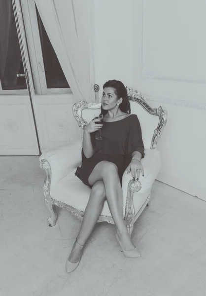 Czarno-białe, w starym fotelu siedzi piękna dziewczyna — Zdjęcie stockowe