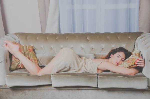 Érdekes lány egy ruhát az ágyon, ölelő egy párnát — Stock Fotó