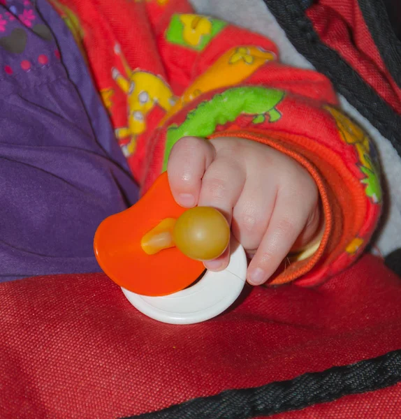 Hand van een baby met een fopspeen. — Stockfoto