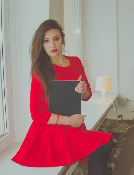 Pencerenin önünde bir kitapla elbiseli güzel bir kız — Stok fotoğraf
