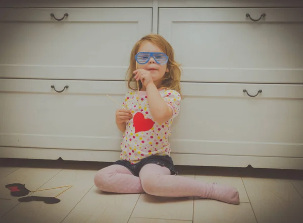 Menina jogando na mascarada, tenta em óculos de sol e coração . — Fotografia de Stock