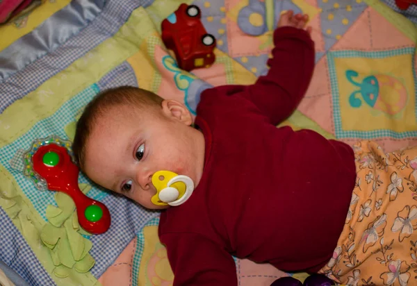 Onder het speelgoed is een kind met een allergie op de wangen — Stockfoto