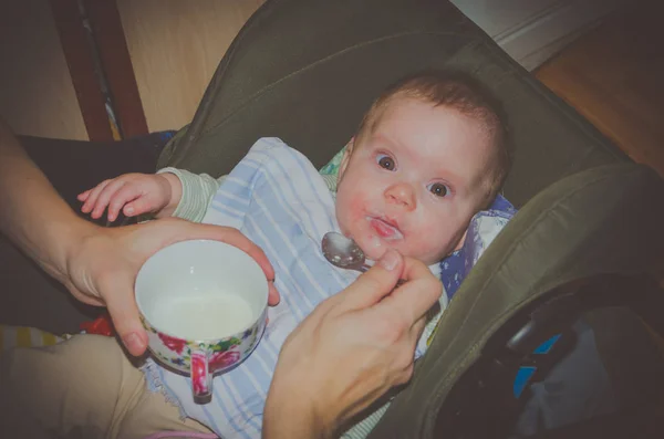 Bebé alimentado con una cuchara sentada en una silla en la cara alergias — Foto de Stock